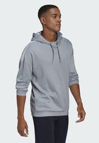 Lichtgrijze hoodie met een gestructureerde afwerking, voorzien van een trekkoord, zijstrepen, een ontspannen pasvorm en ribgebreide manchetten.