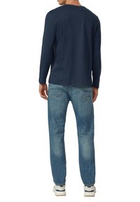 Marineblauw shirt met lange mouwen gemaakt van zacht katoen, gecombineerd met lichtblauwe denim jeans. De outfit heeft een comfortabele pasvorm en een eenvoudig ontwerp.