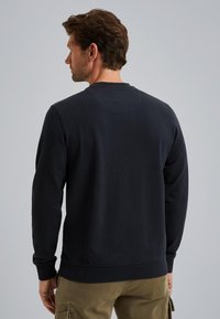 Felpa blu navy con maniche lunghe, polsini a costine e scollo rotondo. Tessuto morbido con una vestibilità rilassata, caratterizzata da un delicato dettaglio di cucitura sul retro.