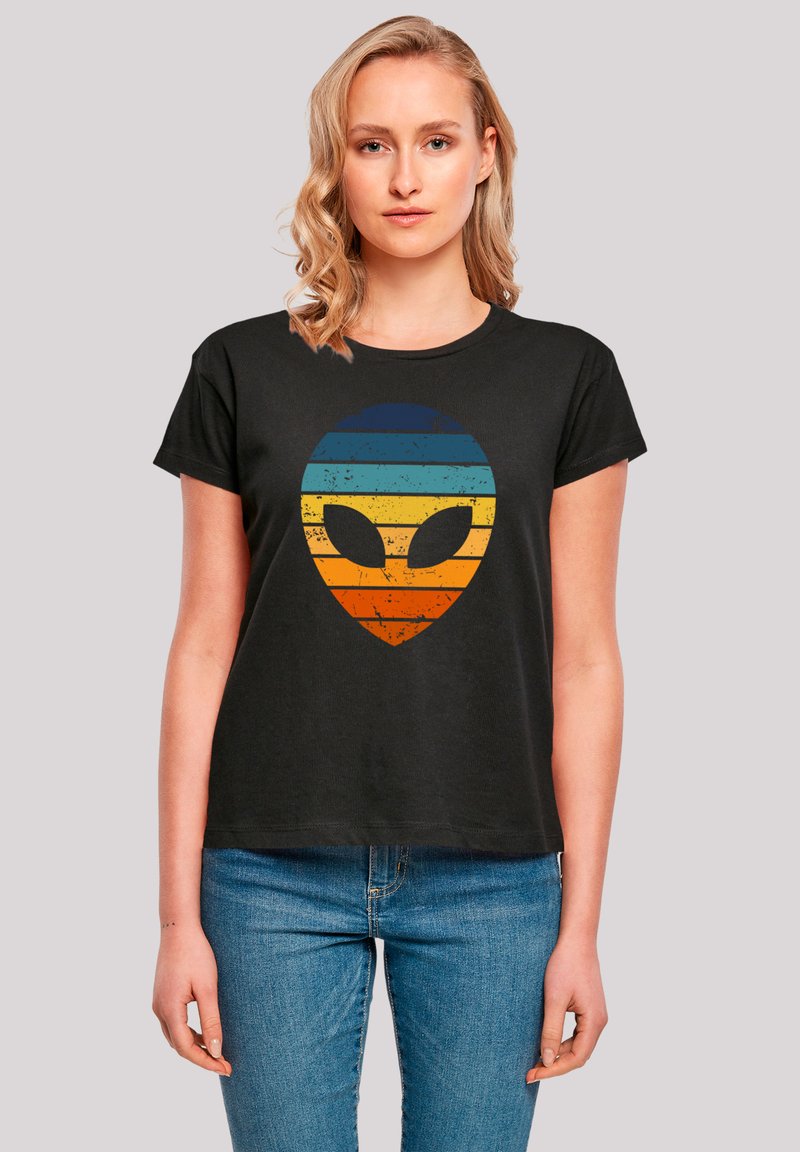Black cotton t-shirt featuring a distressed alien graphic with horizontal stripes in blue, yellow, and orange. Short sleeves and crew neckline.