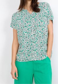 Blomstret kortærmet bluse i let stof med et grønt og gråt mønster på hvid baggrund, med V-hals og afslappet pasform.
