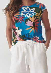 Top con stampa floreale su sfondo blu, con fiori vivaci in rosa, bianco e giallo. Tessuto morbido, scollo rotondo, maniche corte.