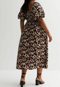 Leopardenmusterkleid mit Puffärmeln, gerafftem Oberteil und knie-langer Rock. Tragen mit schwarzen Riemchenschuhen und figurbetontem Schnitt.