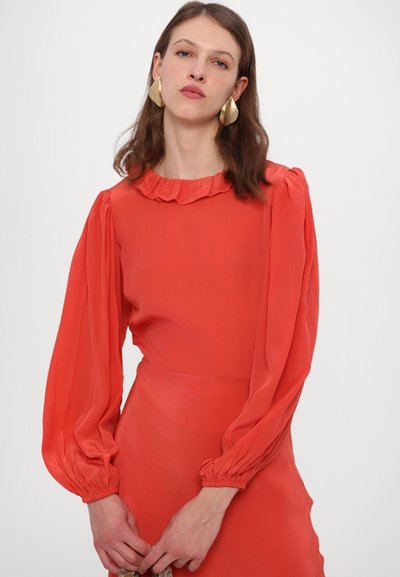 Raudona ilgarankovė suknelė su raukiniais apykaklėje ir pūstomis rankovėmis. Audinys atrodo lygus ir lengvas, su prigludusiu siluetu.