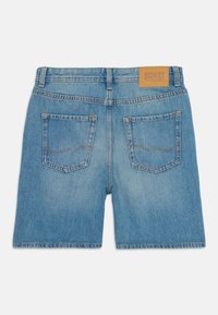 Lyseblå denimshorts med to baglommer, bæltestropper og en tanlæderpatch med teksten "Jack & Jones" på linningen.