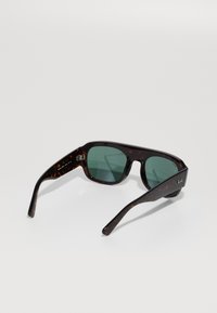 Rudos tortoiseshell saulės akinius su žaliu lęšiu, stačiakampę rėmą ir tiesias kojas. Šone matomas Ray-Ban logotipas.