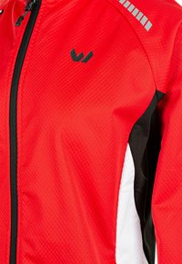 Bright red lightweight jacket with black accents, textured fabric, front zipper, and reflective stripes on the shoulder. Logo in black.