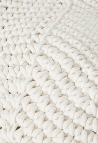 White woven cotton textile with a chunky, textured pattern. Features a soft, thick construction and interlaced loops creating a raised design.