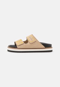 Beige ruskind slidesandaler med to gule velcro-stropper og en sort sål. Har en lagdelt hvid og sort platform-mellemsål.