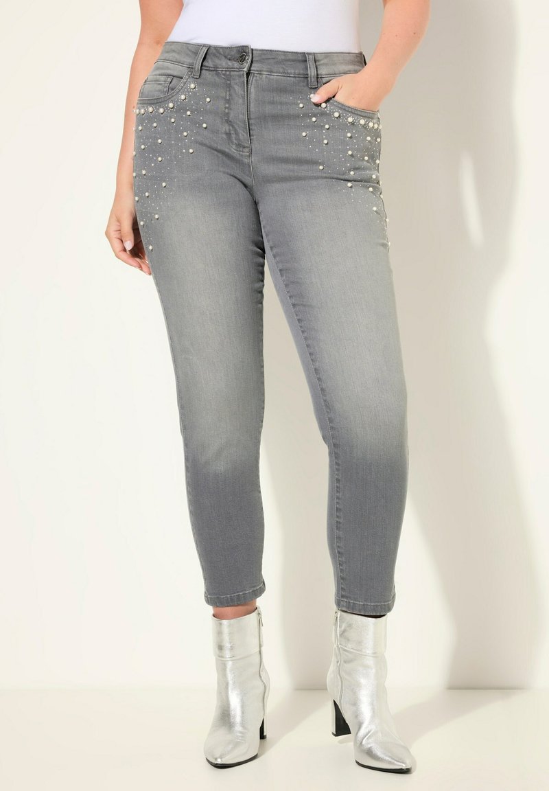 Jeans gris de corte slim con adornos de perlas en los bolsillos, que presentan una cintura de altura media y una textura de denim suave y elástica.
