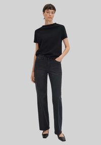 Zwarte kortemouwtop met een ronde hals, gecombineerd met hoog-gesneden, rechtvallende zwarte jeans en spitse zwarte flats. Eenvoudig ontwerp.