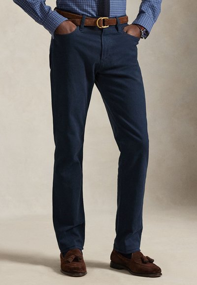 Donkerblauwe chino's van katoen met een recht toelopend model, voorzien van steekzakken aan de voorkant en een bruine leren riem met een gouden gesp.