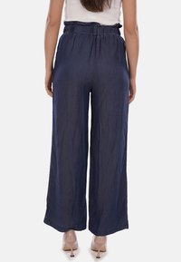 Pantaloni in denim a gamba larga con vita elastica, colore blu navy e tessuto leggero. Presentano una vestibilità ampia senza motivi notevoli.