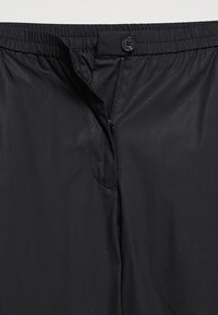Schwarze Hose aus glattem, leichtem Stoff mit elastischem Bund. Verfügt über einen Frontknopfverschluss und einen Reißverschluss für einfaches Anziehen.