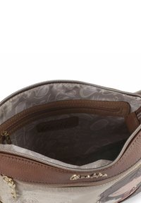 Braune Lederhandtasche mit gemustertem Innenfutter, einschließlich einer Reißverschlusstasche. Verfügt über einen Reißverschluss als Verschluss und ein aufgedrucktes Design auf einer Seite.