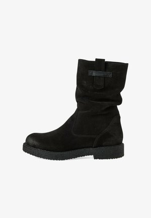 Musta sametist nahast pahkluusaapad, millel on lohku disain, ümar varvas ja tekstuuriga kummitald. Sisaldab kangast silmust pahkluul, et neid oleks lihtne jalga panna.