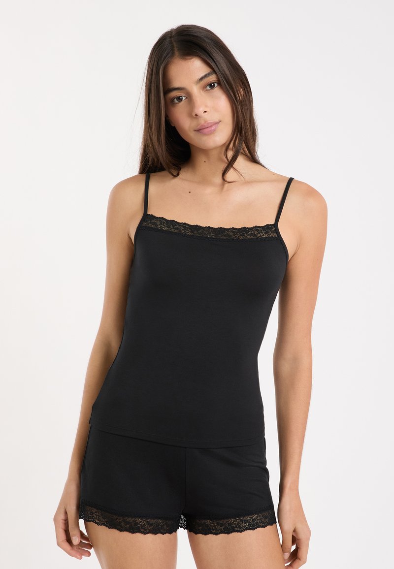 Schwarzes Tanktop- und Shorts-Set mit Spitzensaum an den Rändern. Das Material ist glatt und sorgt für eine figurbetonte Silhouette. Verstellbare Spaghettiträger.