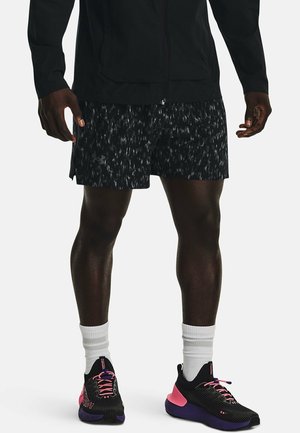 Sorte atletikshorts med et mønster, kombineret med sorte og pink løbesko. Outfittet suppleres med hvide crew-længde sokker.