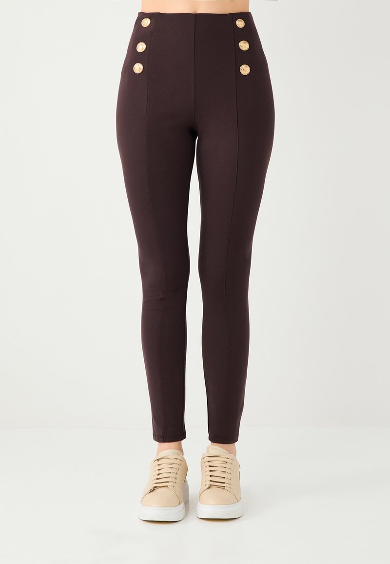 Donkerbruine leggings met hoge taille en een gladde textuur, voorzien van vijf grote gouden knopen aan elke zijde en een slim fit ontwerp.
