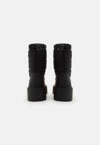 Černé nadýchané zimní boty s vysokou platformou, vybavené elastickými šňůrkami a prošívanou texturou na svršku.