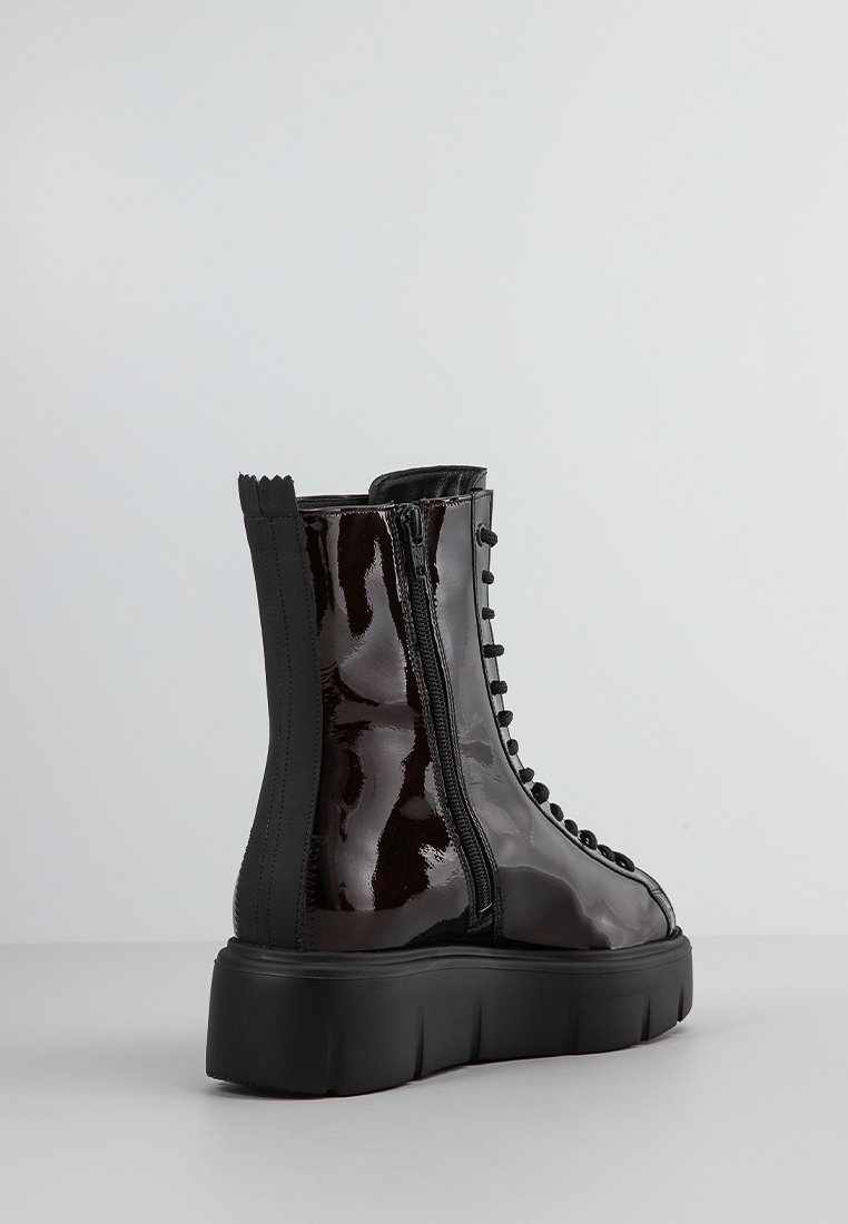 Schwarze Lackleder-Stiefeletten mit einer dicken Sohle, seitlichem Reißverschluss, Schnürdetails und schwarzen Stoffakzenten am oberen Teil.