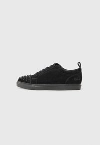 Black suede sneakers with a rounded toe, featuring a spiked design on the front, black laces, and a textured black rubber sole.