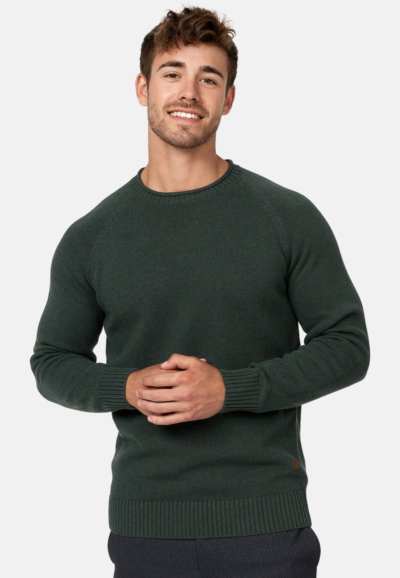 Pull en maille vert foncé avec des bords-côtes aux poignets et à l'ourlet, doté d'un col rond et de manches raglan ; fabriqué à partir d'un tissu texturé.