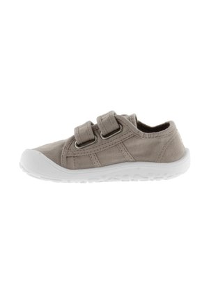 Beige canvas schoen met twee verstelbare banden, ronde neus en witte rubberen zool met een textuurpatroon voor extra grip. Geen zichtbare logo's.