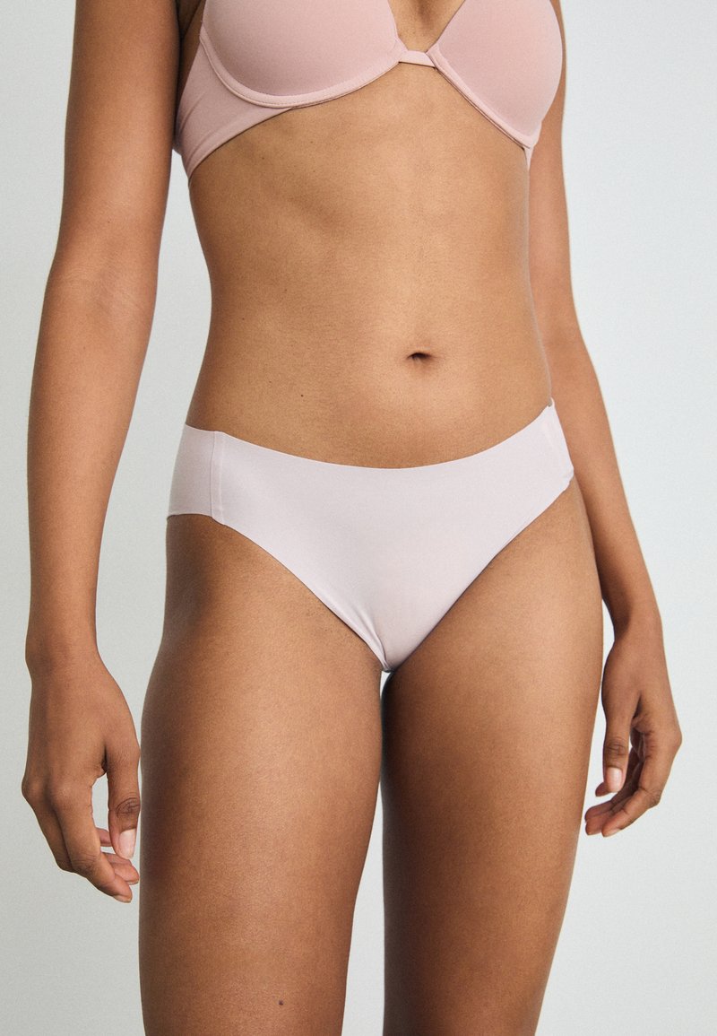 Lys rosa bikini truse laget av glatt stoff, med lavt liv og sømløse kanter for et rent design.