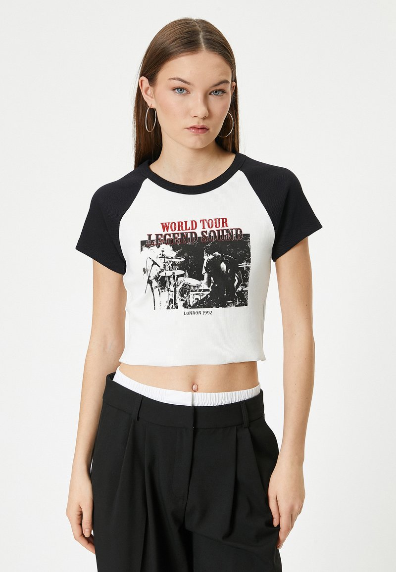 Korte t-shirt in het wit met zwarte raglan mouwen. Bevat een grafische print met de tekst "WORLD TOUR LEGEND SOUND" en "LONDON 1992".