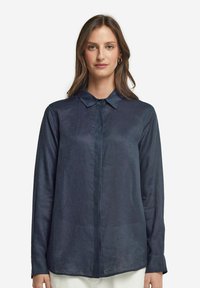 Mörkblå långärmad skjorta i lätt material med spetsig krage, framknäppning och en lätt strukturerad yta.