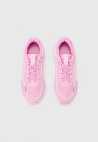 Roze sportschoenen met een gebreide textuur, afgeronde neus, vetersluiting en een reflecterend zilveren logo aan de zijkant. Zachte roze binnenvoering.