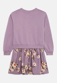 Lila sweatshirtklänning med en texturerad överdel och en blommönstrad kjol med vita blommor och gröna inslag. Elastiska ärmslut och nederkant.