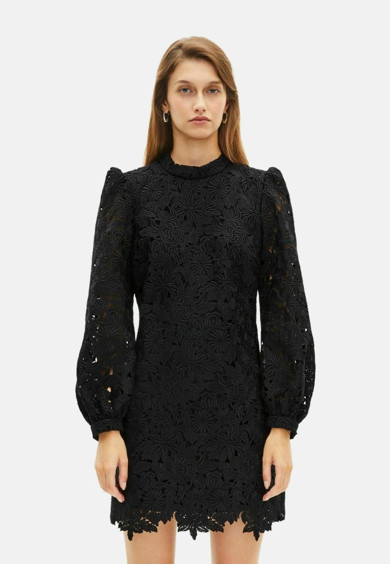 Schwarzes Spitzenkleid mit floraler Stickerei, hohem Ausschnitt und Puffärmeln. Der Saum hat ein gewelltes Design, das kunstvolle Details zur Schau stellt.