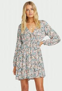 Robe fleurie dans des couleurs pastel, avec des manches longues, un col en V et une taille froncée, offrant une silhouette fluide et ample.