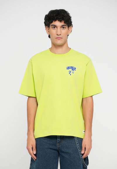 Neon yellow short-sleeve t-shirt made of cotton, featuring a blue graphic design on the left chest area. Straight-cut hem and relaxed fit.