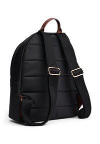 Black quilted backpack with adjustable black straps and a brown leather handle on a white background.