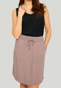 Černý top bez rukávů v kombinaci s lehce růžovou sukní po kolena s elastickým pasem a dvěma předními kapsami. Měkká, lehká látka.