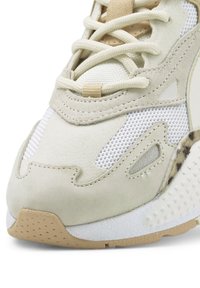 Light beige sneaker featuring a combination of smooth suede, mesh panels, and textured soles, with lace-up design and subtle accents.