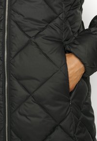 Black quilted puffer jacket with a zippered front and side pockets. Features diamond stitching and a smooth, shiny fabric texture.
