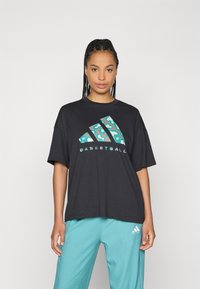 Zwarte oversized t-shirt van katoen met een kleurrijk luipaardprintontwerp op het Adidas-logo en het woord "BASKETBALL" eronder.