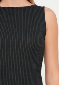 Black sleeveless top featuring vertical pinstripes, a round neckline, and a smooth texture, designed for a fitted silhouette.