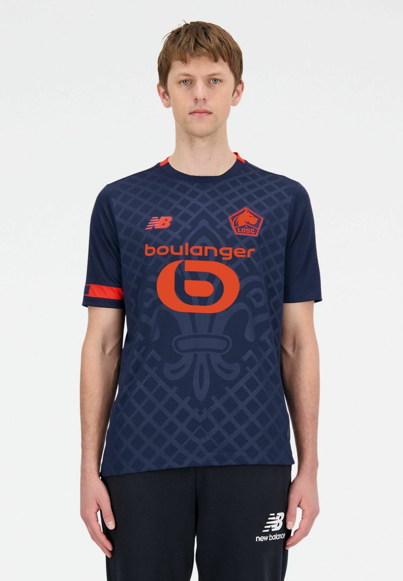 Jersey deportivo azul marino con un patrón geométrico, que presenta un logo y acentos en naranja. Fabricado con un material transpirable, de manga corta y con diseño de cuello redondo.