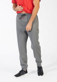 Grijze gebreide sweatpants met een elastische tailleband, trekkoordaccenten, taps toelopende benen en zijzakken, gedragen met zwarte sneakers.