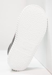 Scarpa in tela grigia con una suola in gomma bianca testurizzata, dotata di tacco piatto e marchio stampato sulla suola, "Victoria Made in Spain."