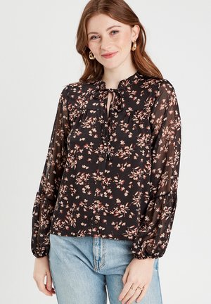 Schwarze Bluse mit Blumenmuster aus transparenter Stoff, mit einer Krawatten-Nackenpartie, langen Ballonärmeln und einer durchgehenden Knopfleiste mit rosa und cremefarbigen Blumenmustern.