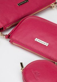 Portafogli in pelle fucsia, con una finitura testurizzata, cerniere dorate e accenti con logo. Un portafoglio ha una forma rettangolare; l'altro è rotondo.