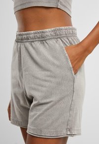 Shorts en coton gris avec taille  élastique et poches latérales, présentant une texture douce et une coupe décontractée.