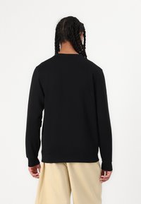 Black crewneck sweatshirt with long sleeves, a smooth texture, and ribbed cuffs. The back is plain, showing no logos or designs.