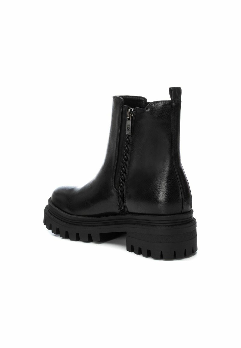 Bottines en cuir noir avec fermeture éclair sur le côté, semelle à crantage épais et finition lisse. Design court et ajusté avec une languette à l'arrière.